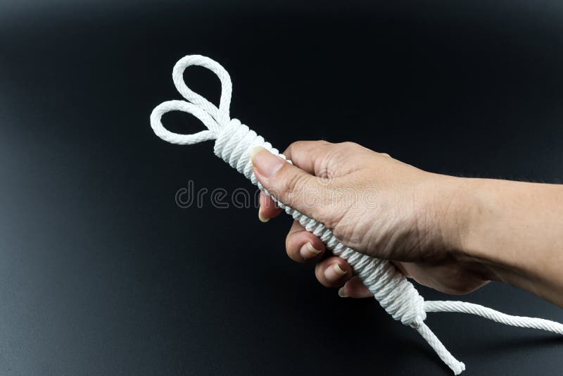 White rope in hand on black background stock photo White rope in hand on black background stock photo
