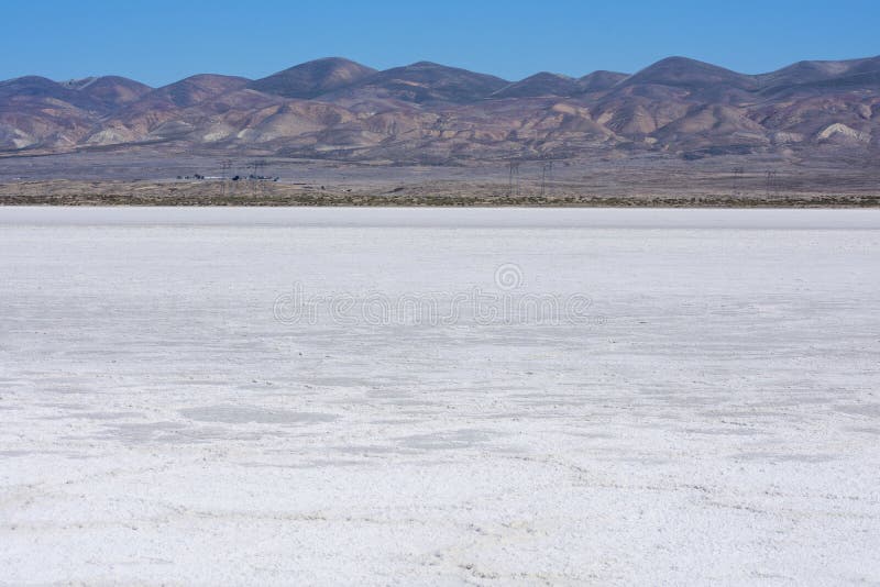 White salt flats of dry Soda Lake at Carrizo Plain National Monument with power line near lake shore. Temblor Range mountains on