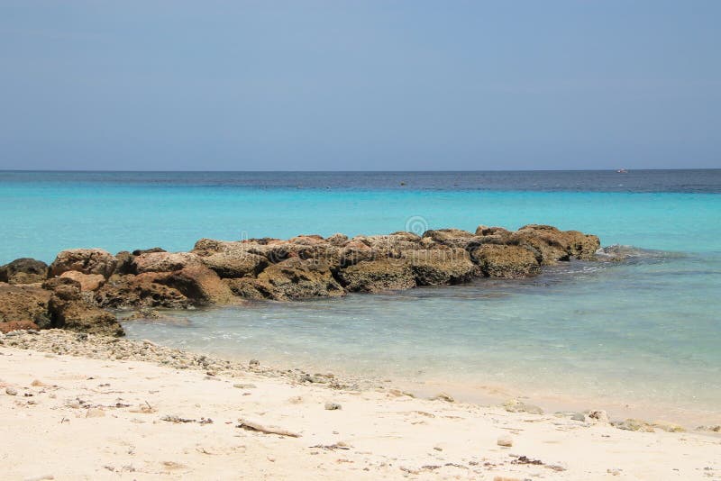 Ocean view. White sand, blue sea and a water breaker. Tropical beach. White sand, blue sea and a water breaker made of rocks. Ocean view stock photo Ocean view. White sand, blue sea and a water breaker. Tropical beach. White sand, blue sea and a water breaker made of rocks. Ocean view stock photo