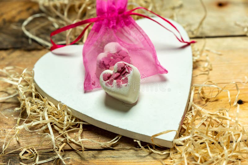 I love you - white, simple heart cut from wood on a romantic, simple rustic background next to two white, hearts shaped chocolates stock photography I love you - white, simple heart cut from wood on a romantic, simple rustic background next to two white, hearts shaped chocolates stock photography