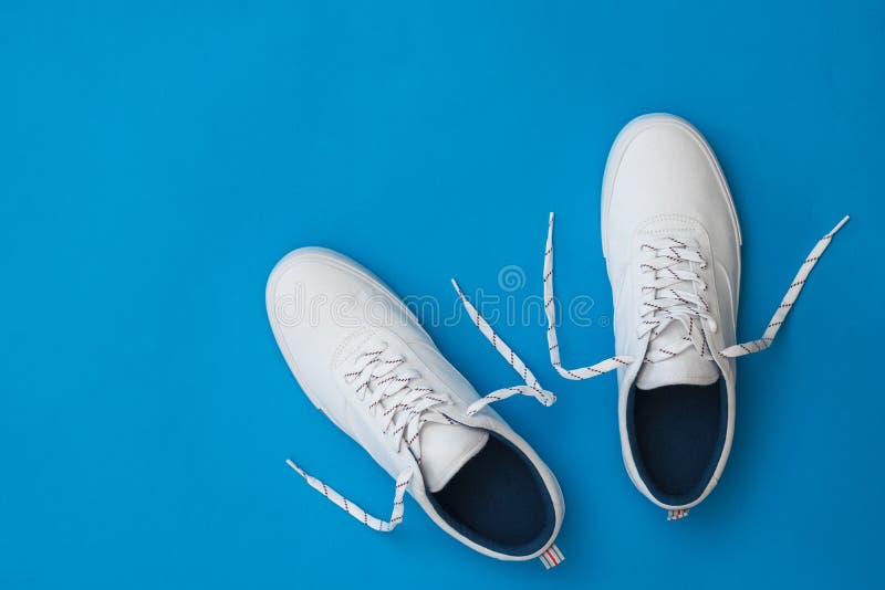 White Sneakers with Untied Laces on a Blue Background. Sports Style ...