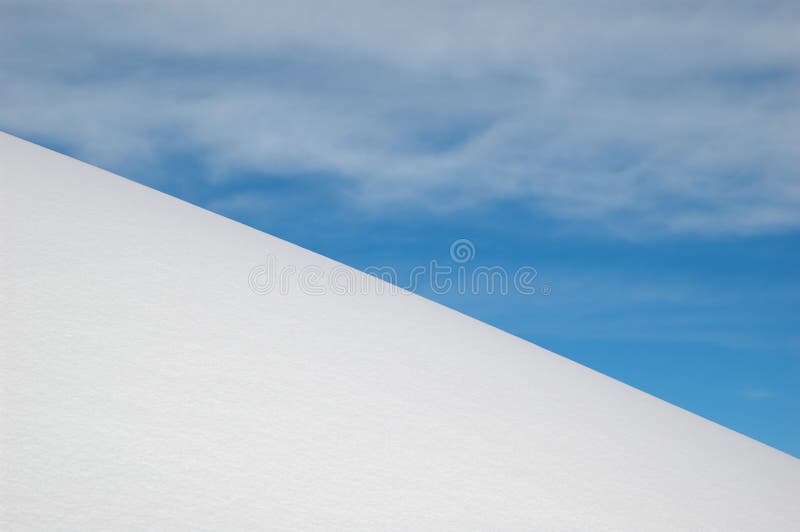 White snow slope, blue sky and white clouds stock image