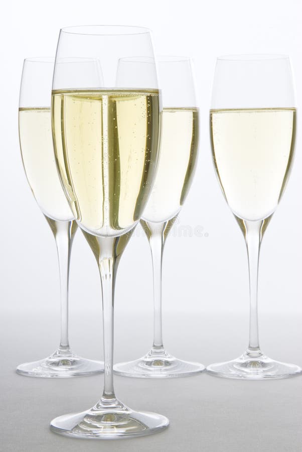 Four glasses of white sparkling wine backlit.