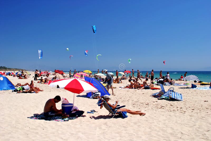 White, sunny, sandy beach full of kitesurfers in Tarifa, Spain