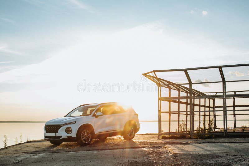 White compact SUV car with sport and modern design parked on concrete road by the sea near the beach at sunset royalty free stock photography White compact SUV car with sport and modern design parked on concrete road by the sea near the beach at sunset royalty free stock photography