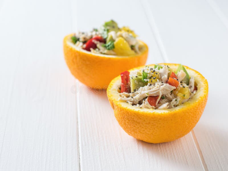 White table with two orange halves filled with salad.