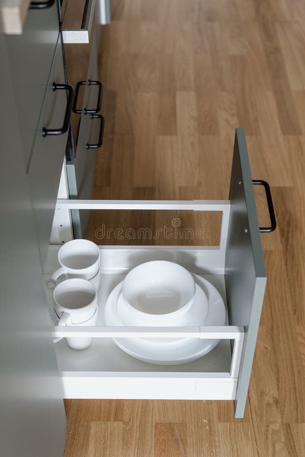 White tableware with plates and cups in kitchen drawer