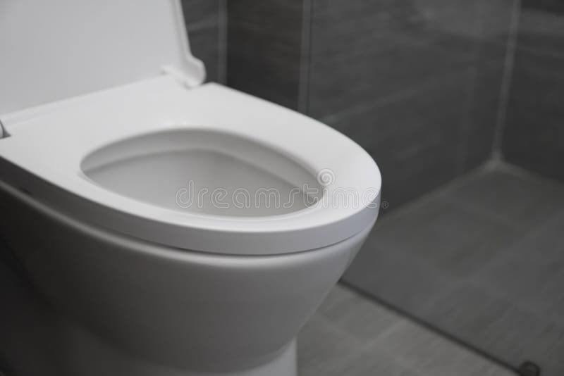 White Toilet Bowl in a Bathroom. Closeup View of a Flushing White Toilet. the Water Swirls in