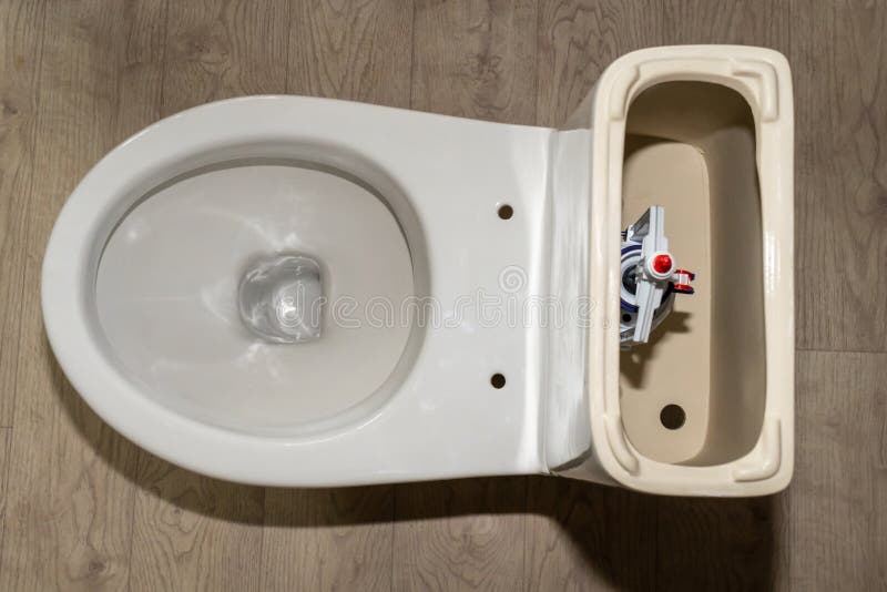 White Toilet Tank with an Open Lid and Flush System. Plastic Toilet