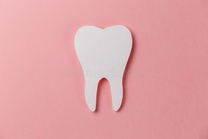 White tooth on pink background. Oral dental hygiene. Teeth whitening. Dental health concept. Oral care, teeth restoration. Dentist day concept. Flat lay. Top view. Pastel colors