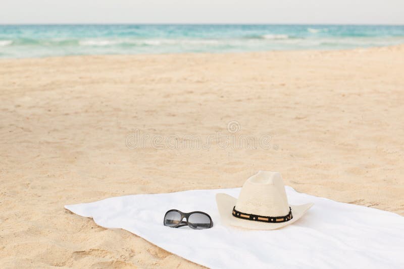White towel on the beach with sunglasses and hat