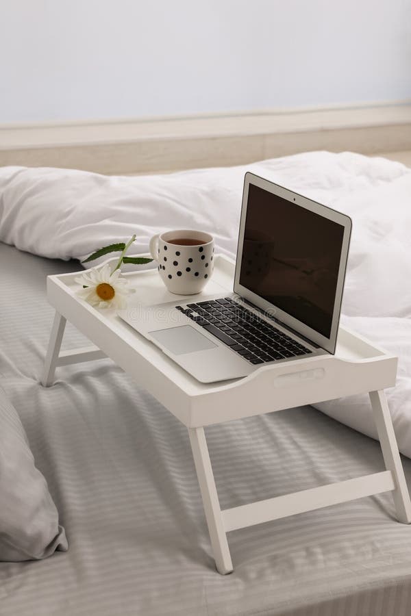 White Tray Table with Laptop, Cup of Drink and Daisy on Bed Indoors