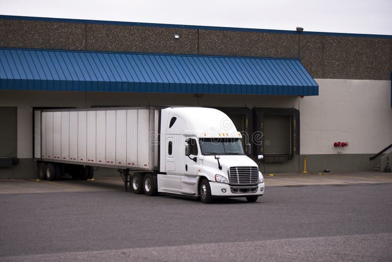 White truck with a trailer in a warehouse on the unloading stock photo