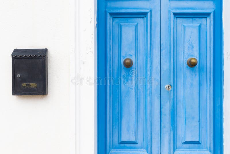 White wall with closed blue wooden doors and a black mail box royalty free stock photos