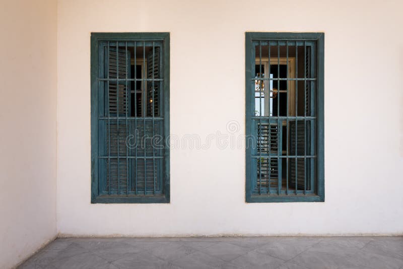 White wall with grunge windows with wooden green shutters and wrought iron bars and marble floor stock images White wall with grunge windows with wooden green shutters and wrought iron bars and marble floor stock images