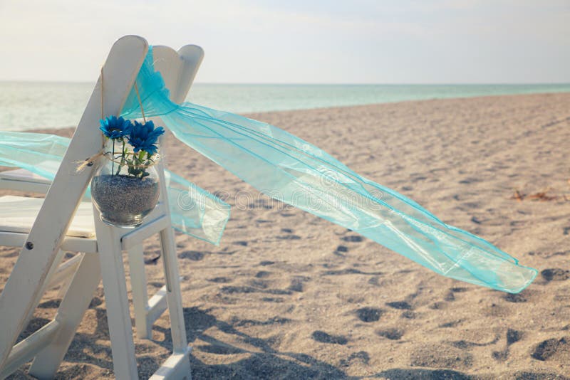 White Wedding Chair with Blue Decoration on the Beach