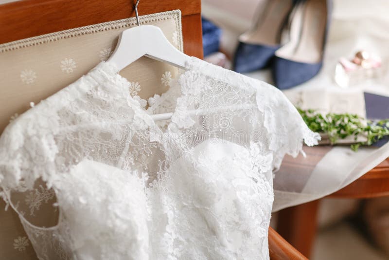 White wedding dress with lace lying on the chair. bouquet different flowers. Modern bridal bunch with poppy flower and