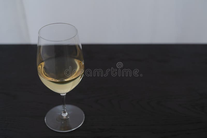 White Wine in a Wineglass on Black Oak Table with Copy Space Stock