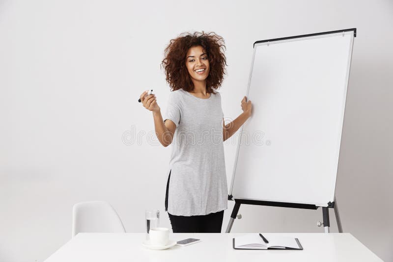 Whiteboard африканской дамы дела усмехаясь стоящее близко пустое сухое в открытом пространстве офиса, объясняя ее идею применения стоковая фотография rf Whiteboard африканской дамы дела усмехаясь стоящее близко пустое сухое в открытом пространстве офиса, объясняя ее идею применения стоковая фотография rf