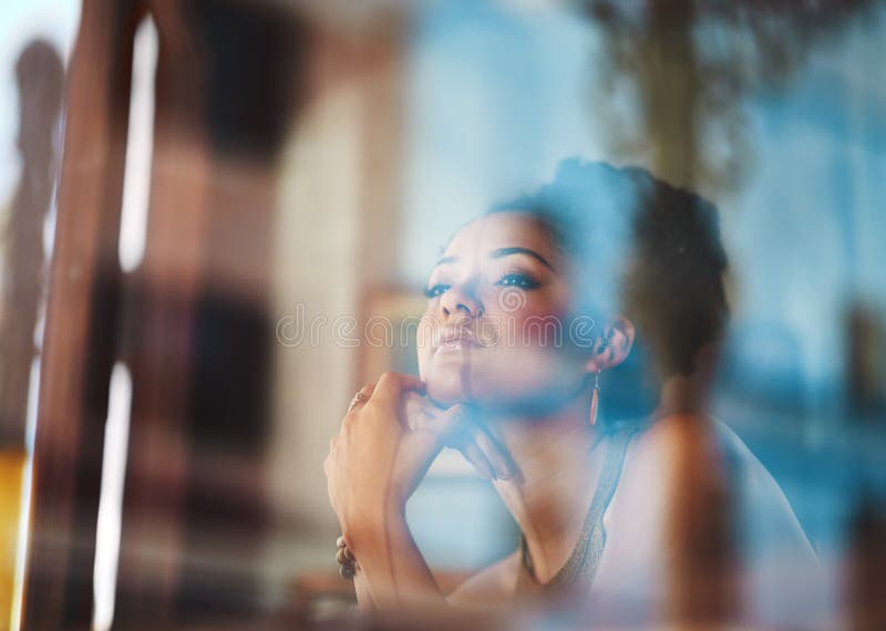 Who doesnt love a window seat. an attractive young woman sitting in a coffee shop.