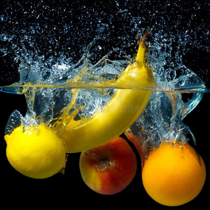 Whole banana, orange, lemon and apple in water on a black background. Fresh fruit with water spray