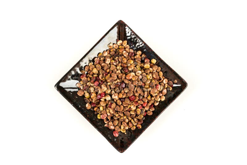 Whole Dried Sumac Berries in a Black Ceramic Plate Over White Top Down