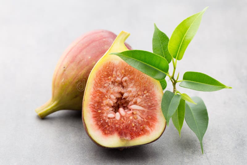 Whole Figs and One Fig Sliced in Half on Top of a Gray Table. Stock