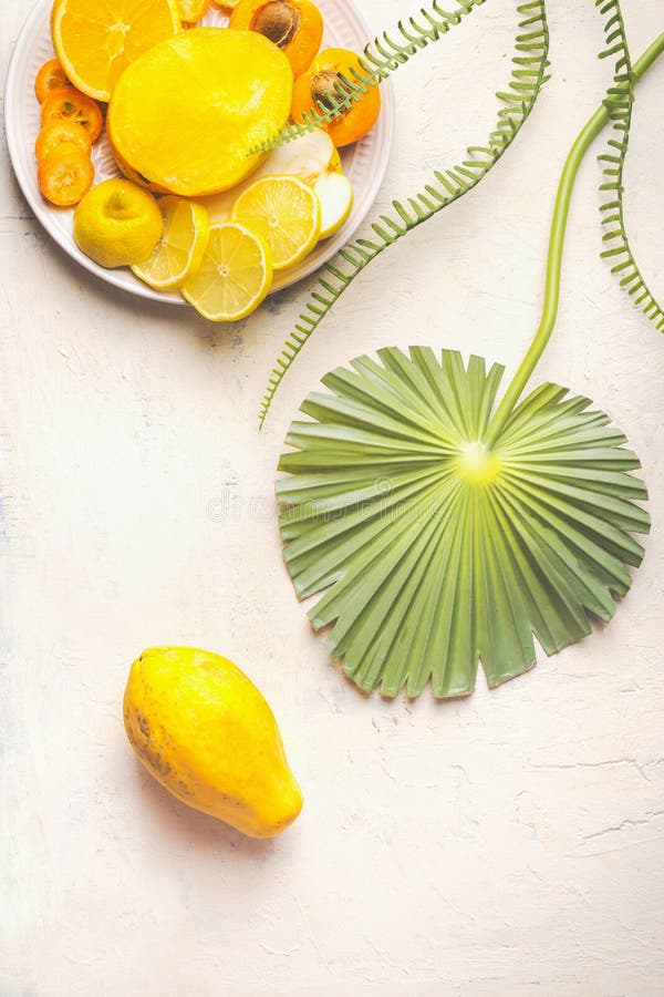 Whole papaya fruit on white table with tropical leaves and plate with yellow sliced fruits, top view. Summer food. Healthy eating royalty free stock images Whole papaya fruit on white table with tropical leaves and plate with yellow sliced fruits, top view. Summer food. Healthy eating royalty free stock images