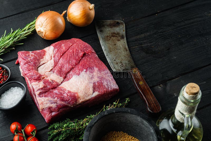 A whole piece of raw Beef Brisket,with ingredients for smoking  making  barbecue, pastrami, cure, on black wooden table background