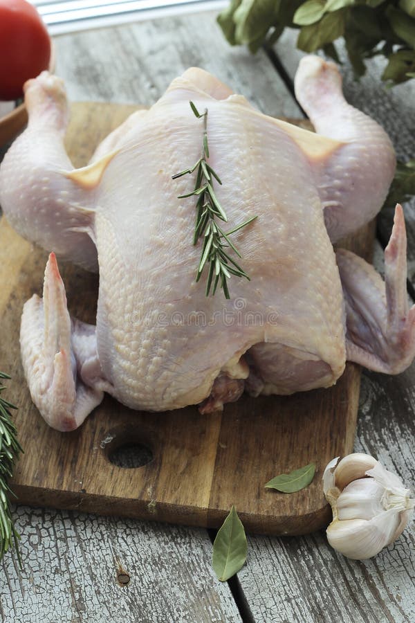 Whole Raw Chicken with Rosemary on a Cutting Board Stock Photo Image