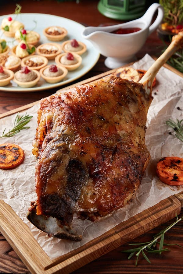Whole roasted lamb leg on wooden cutting board stock photo Whole roasted lamb leg on wooden cutting board stock photo