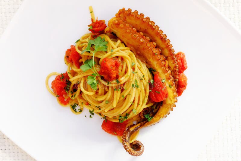 Whole spaghetti seasoned with octopus with tomato and turmeric. Genuine octopus