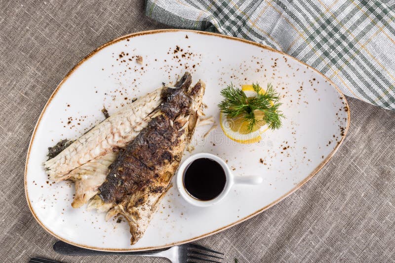 Whole Trout Fish Grilled with Lemon and Soy Sauce on the Table Stock