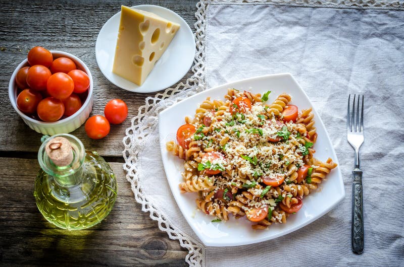 Whole wheat fusilli pasta with cheese and cherry tomatoes stock photo
