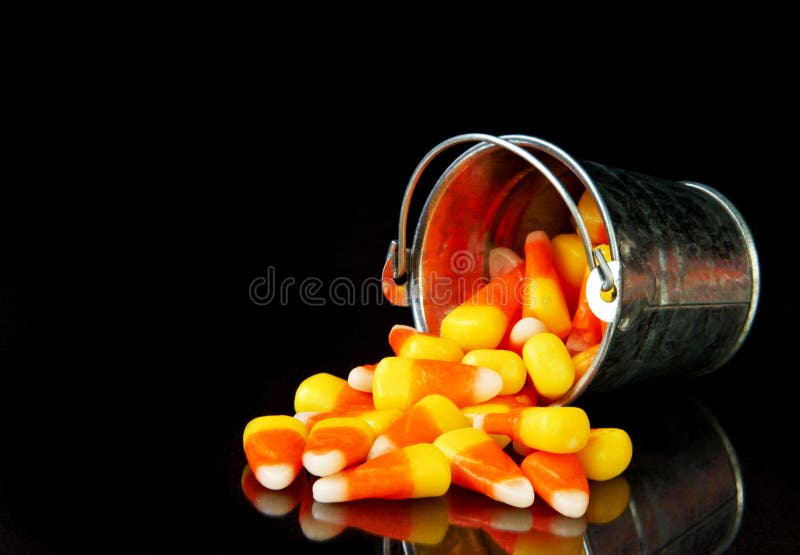 Bucket of candy corn on a black background with reflection. Bucket of candy corn on a black background with reflection