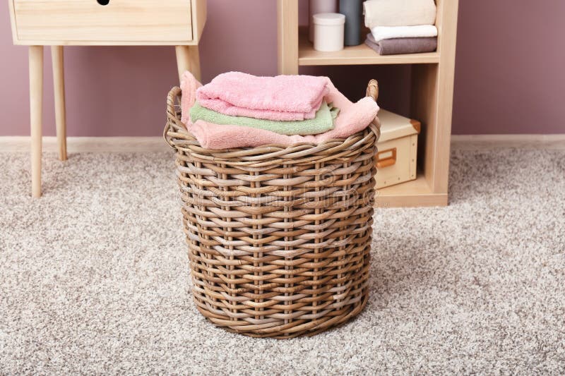 Wicker Basket with Folded Clean Towels on Floor in Bathroom Stock Photo