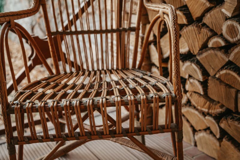 Wicker chair stands next to chopped wood