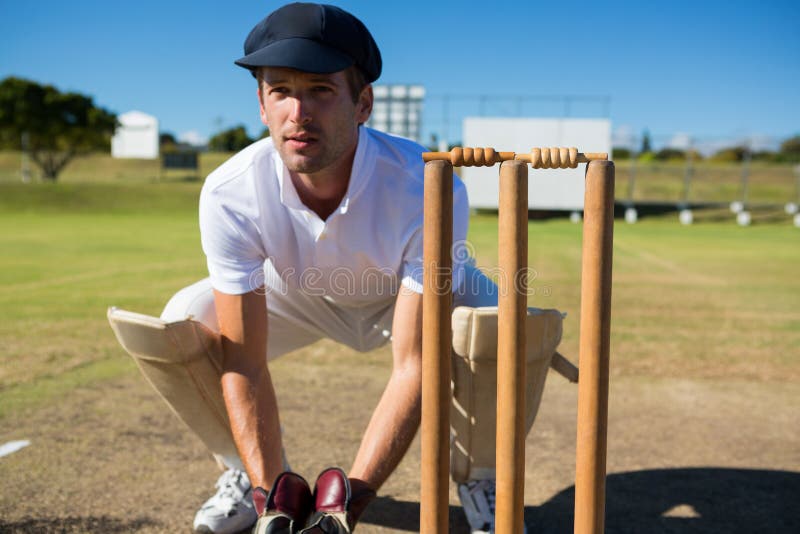 Wicket keeper crouching by stumps during match stock image Wicket keeper crouching by stumps during match stock image