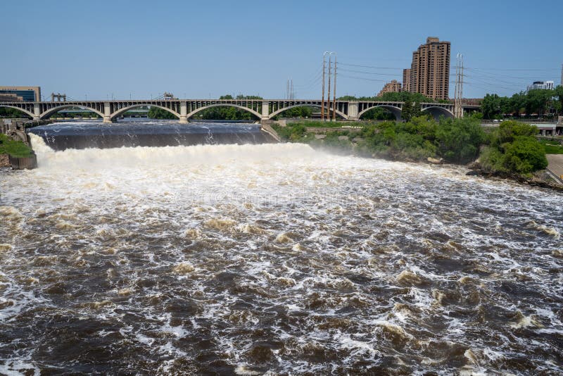 Wide angle view of St. Anthony Falls in downtown Minneapolis, Central Avenue Bridge in background. Fast currents create foamy stock image Wide angle view of St. Anthony Falls in downtown Minneapolis, Central Avenue Bridge in background. Fast currents create foamy stock image