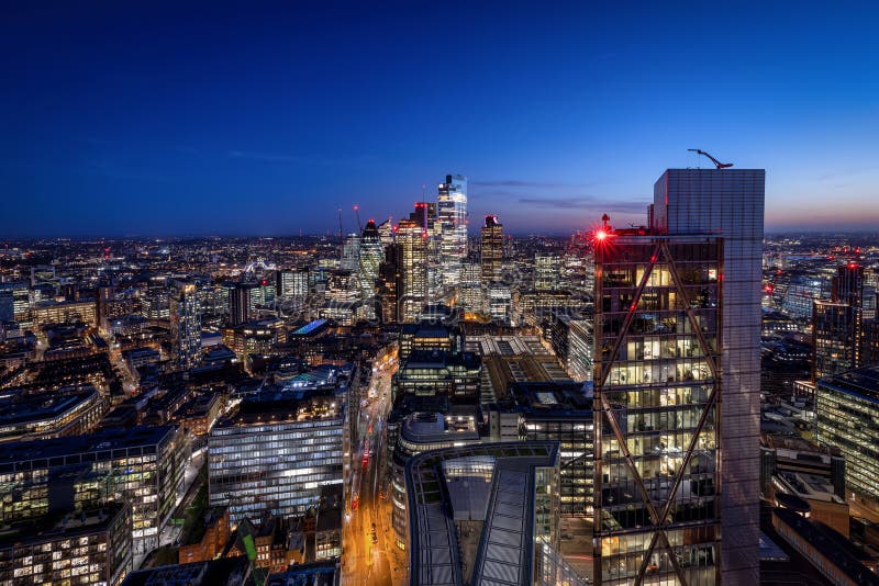 Wide panoramic night view of the skyline of London with the illuminated office skyscrapers until back to the famous Tower Bridge and river Thames