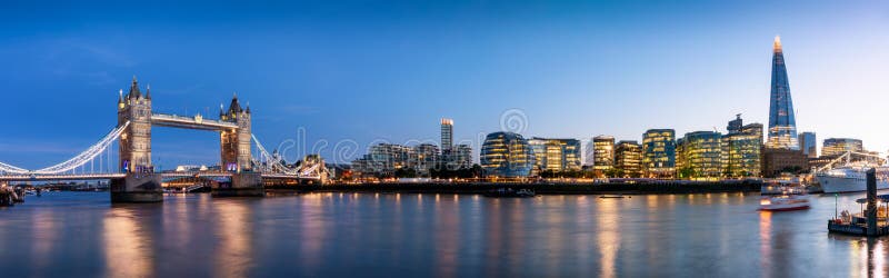 Wide panoramic view to the urban skyline of London with the illuminated, modern office buildings along the Thames river, UK. Wide panoramic view to the urban skyline of London with the illuminated, modern office buildings along the Thames river, UK