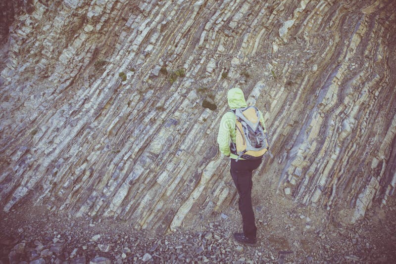 Wide shot of a male wearing a green jacket trying to climb the hill.