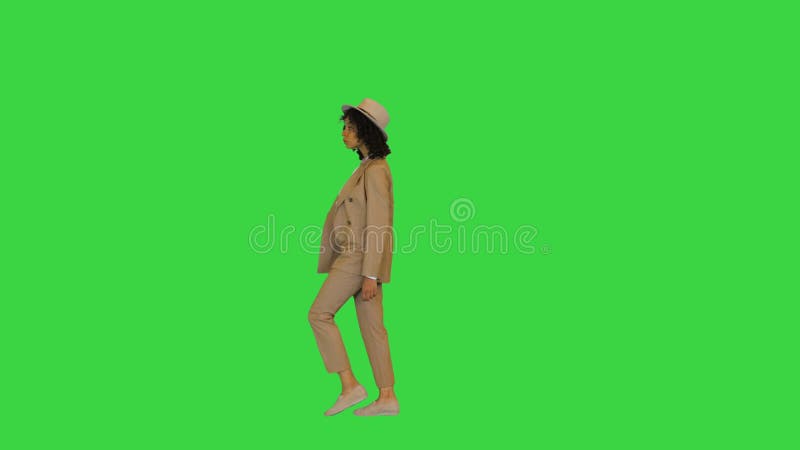 Young black lady wearing a hat walking on a Green Screen, Chroma Key.