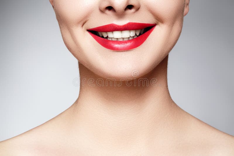 Wide smile of young beautiful woman with perfect healthy white teeth on grey background. Dental whitening, ortodont, care tooth and wellness. Red lipstick makeup on female lips. Wide smile of young beautiful woman with perfect healthy white teeth on grey background. Dental whitening, ortodont, care tooth and wellness. Red lipstick makeup on female lips.