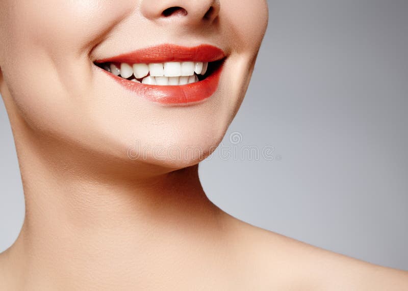 Wide smile of young beautiful woman with perfect healthy white teeth on grey background. Dental whitening, ortodont, care tooth and wellness. Red lipstick makeup on female lips. Wide smile of young beautiful woman with perfect healthy white teeth on grey background. Dental whitening, ortodont, care tooth and wellness. Red lipstick makeup on female lips.