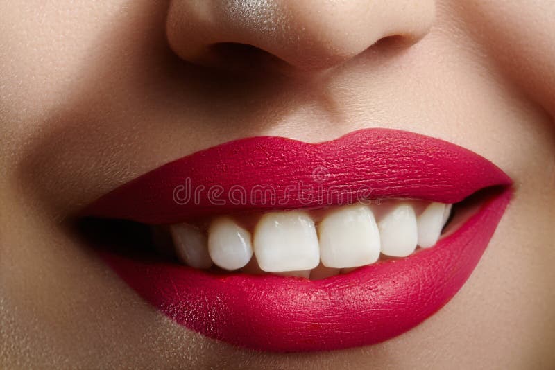 Wide smile of young beautiful woman with perfect healthy white teeth on grey background. Dental whitening, ortodont, care tooth and wellness. Red lipstick makeup on female lips. Wide smile of young beautiful woman with perfect healthy white teeth on grey background. Dental whitening, ortodont, care tooth and wellness. Red lipstick makeup on female lips.