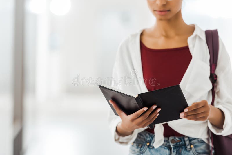 Widok amerykańskiego studenta z notebookiem w korytarzu uniwersyteckim. Widok z widokiem na afrykańskiego amerykańskiego studenta z notebookiem w korytarzu uniwersyteckim
