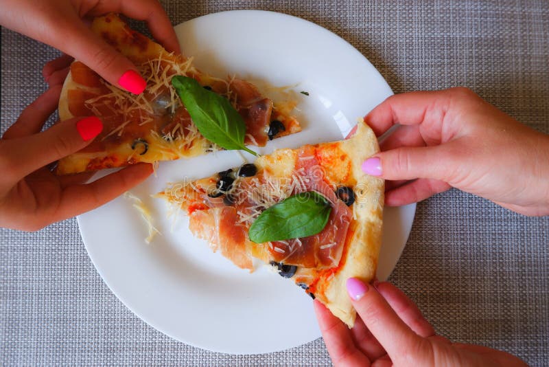 Widok z bliska na kobiecą dłoń zabiera kawałek pizzy z białej płytki. apetyt na pyszną pizzę fotografia royalty free