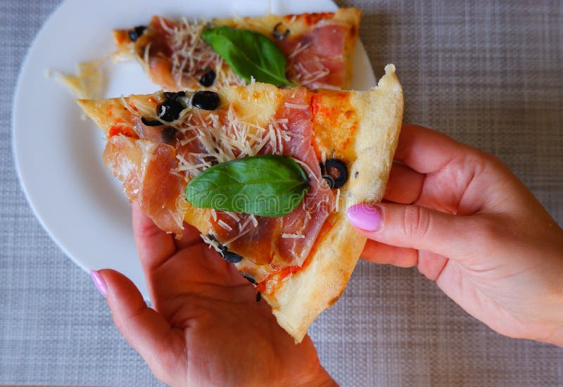 Widok z bliska na kobiecą dłoń zabiera kawałek pizzy z białej płytki. apetyt na pyszną pizzę zdjęcie stock