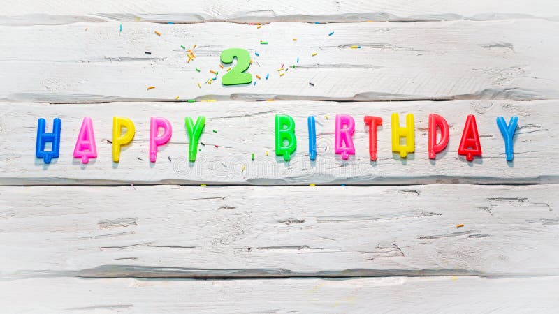 Top view of happy birthday candle numbers copy space on wooden white pastel boards. Beautiful birthday card with number 2. Top view of happy birthday candle numbers copy space on wooden white pastel boards. Beautiful birthday card with number 2